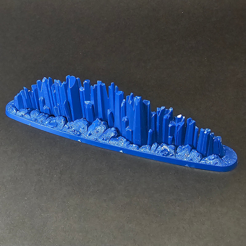 A blue, oval-shaped Used Warhammer Age of Sigmar: Prismatic Palisade Endless Spell with jagged blue spikes on a textured base.