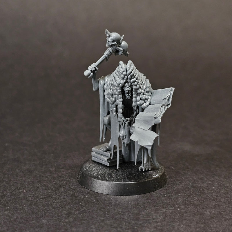 Used Warhammer Age of Sigmar: Flesh Eater Courts - Grand Justice Gormayne: A gray mini of the skeletal, robed mage with staff, beside an open book on a stand, scrolls and books at his feet on a round base.