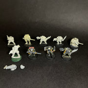 Ten used Warhammer 40k: Space Marines - Scouts stand on a dark surface—three painted in black and yellow, others unpainted. Two loose pieces are included in front of the figurines.