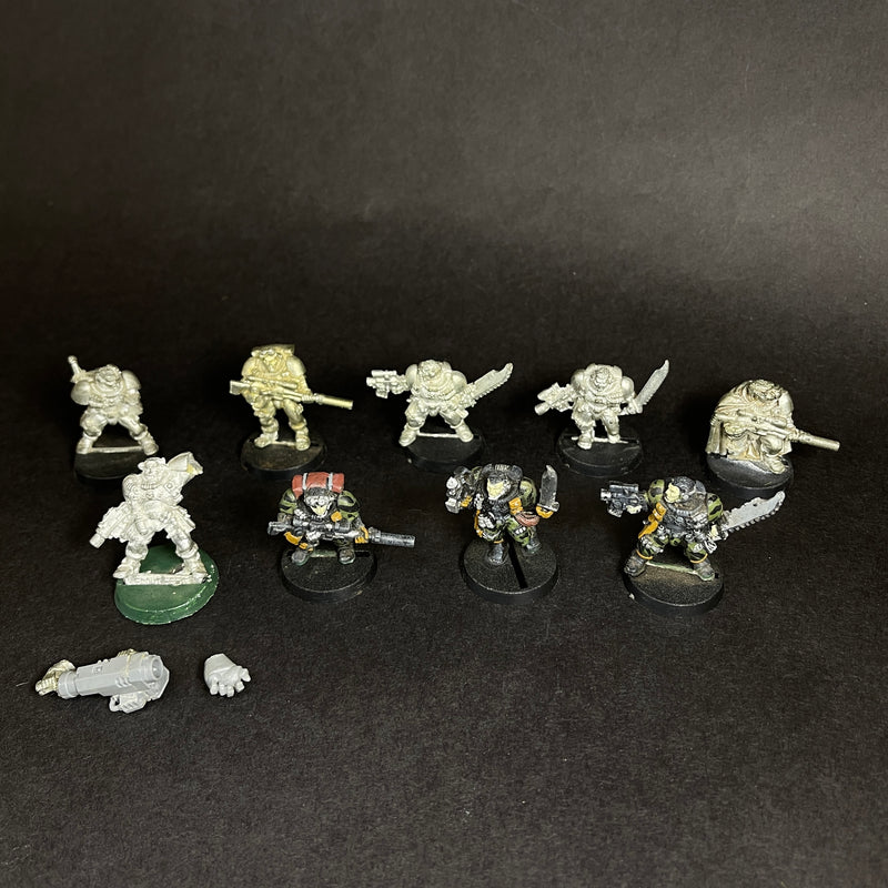 Ten used Warhammer 40k: Space Marines - Scouts stand on a dark surface—three painted in black and yellow, others unpainted. Two loose pieces are included in front of the figurines.