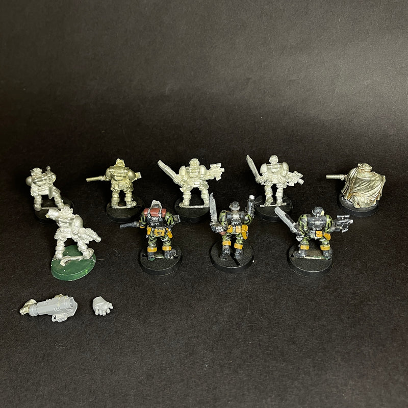 A group of painted and unpainted Used Warhammer 40k: Space Marines - Scouts, including old metal models, arranged in two rows on a dark surface with loose bits like a hand and gun in front.