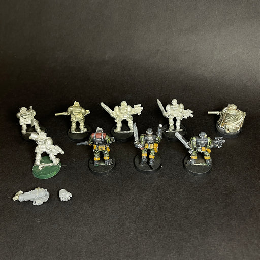A group of painted and unpainted Used Warhammer 40k: Space Marines - Scouts, including old metal models, arranged in two rows on a dark surface with loose bits like a hand and gun in front.