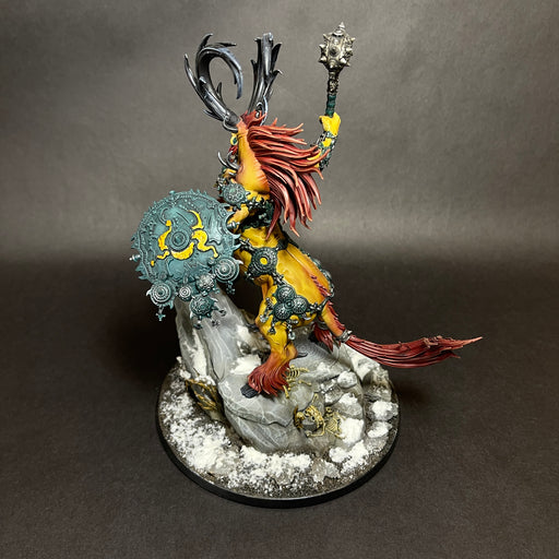 A painted Used Warhammer Age of Sigmar: Destruction - Kragnos, the End of Empires miniature, depicting a beast-like warrior with a red mane, horns, ornate armor, shield, and mace, stands on a snowy rock base against a black background.