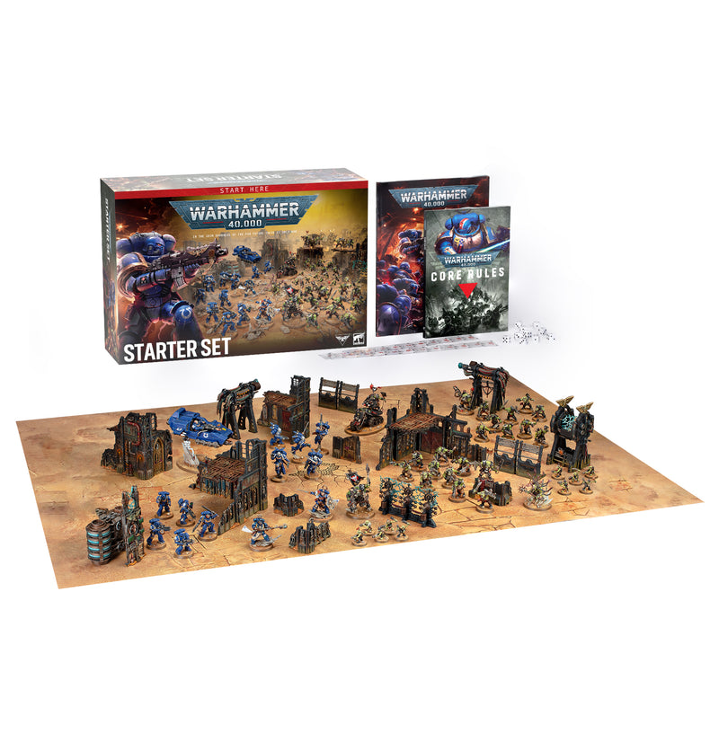 Warhammer 40k: Starter Set with box, rulebook, and assembled painted miniatures displayed on a detailed battlefield mat complete with terrain and accessories from Games Workshop.