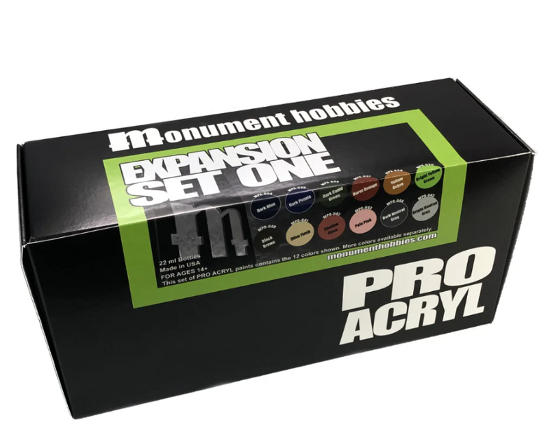 A black box labeled Monument Hobbies Pro Acryl Paint: Expansion Set #1 – 12 Colors includes 12 new paint bottles, with sample swatches and product details shown on the packaging.