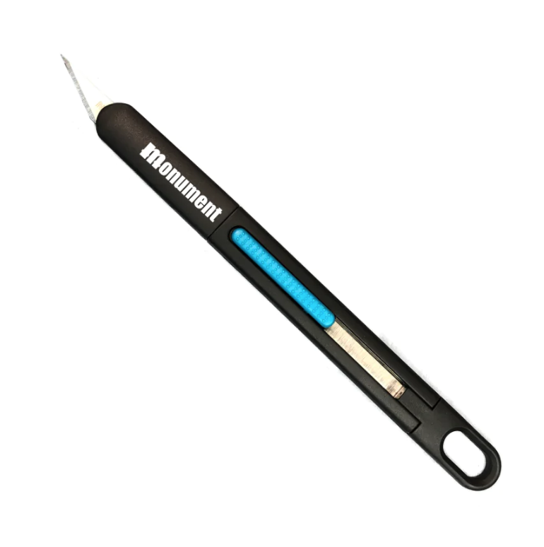 The Monument Hobbies Monumentools Retractable Hobby Knife features a black body, sharp replaceable blade, blue grip, and a hole at the handle’s end for hanging.